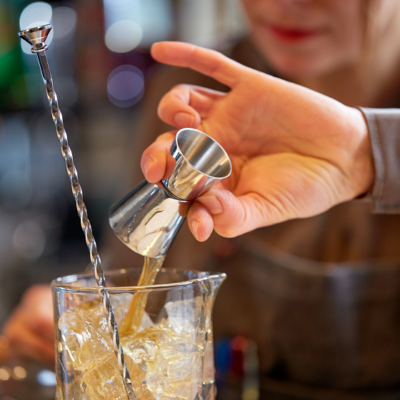 woman bartender with jigger as tool for pouring