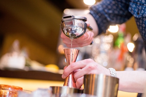man straining juice into jigger