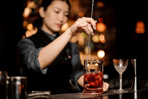 female bartender using bar spoon
